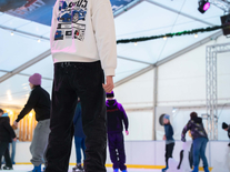 Jugendlicher auf Schlittschuhen unter farbigen Scheinwerfern auf der überdachten Eisbahn