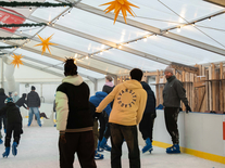 Besucher fahren unter Sternen und Lichterketten auf der überdachten Eisbahn ihre Runden