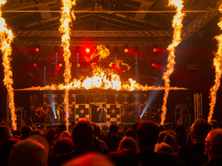 Band auf der Bühne mit Feuershow und Publikum vor der Konzertbühne