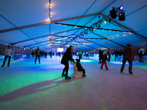 Besucher laufen unter Sternen, Lichterketten und farbiger Beleuchtung über die Eisfläche