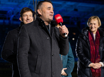 Mann mit rotem Mikrofon bei einer Ansprache auf dem Spielfeld während des Weihnachtssingens