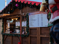Winterlich geschmückter Getränkestand mit Holzhütte und Speisekarte im Gastronomiebereich der Eiswelt Jena